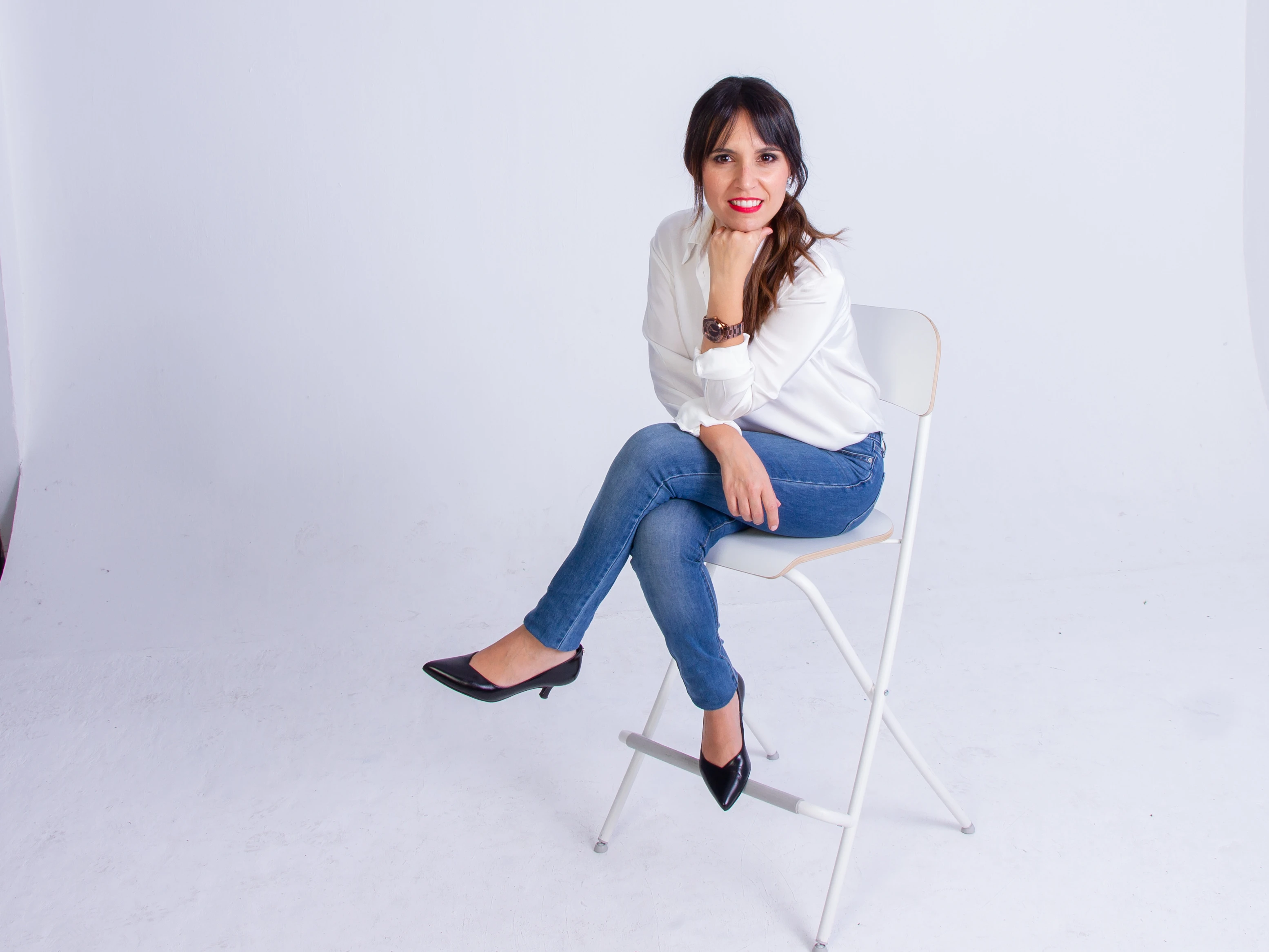 Almudena Lebrero, psicóloga sanitaria, sentada y sonriendo, con blusa blanca